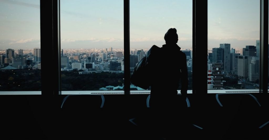 man standing at airport window looking at the city
