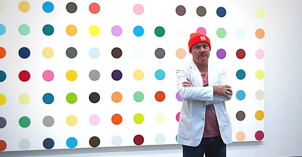 Damien Hirst standing in front of his art work